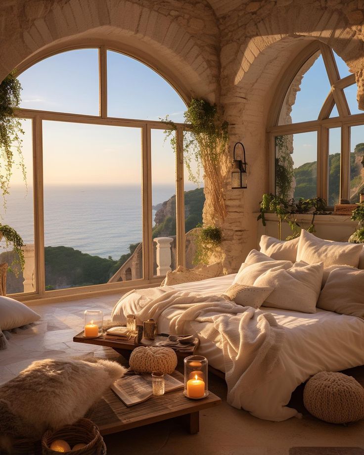 a bedroom with an arched window overlooking the ocean and candles in front of it on a coffee table