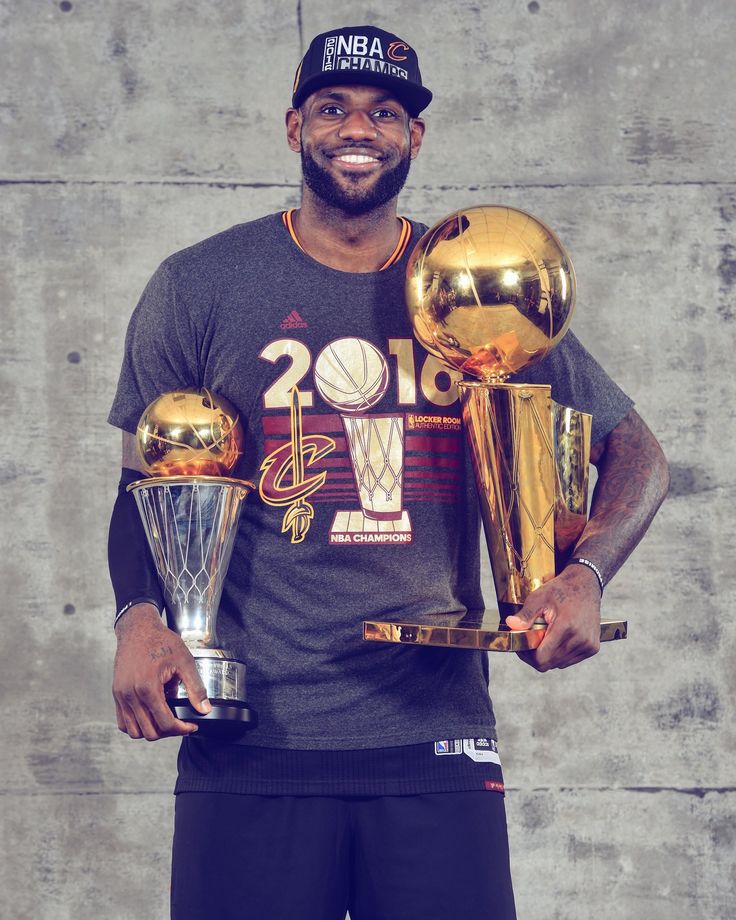 the basketball player is holding trophies in his hands