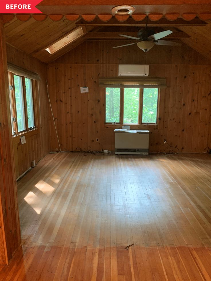 an empty room with wood paneling and ceiling fan in the center, windows on both sides