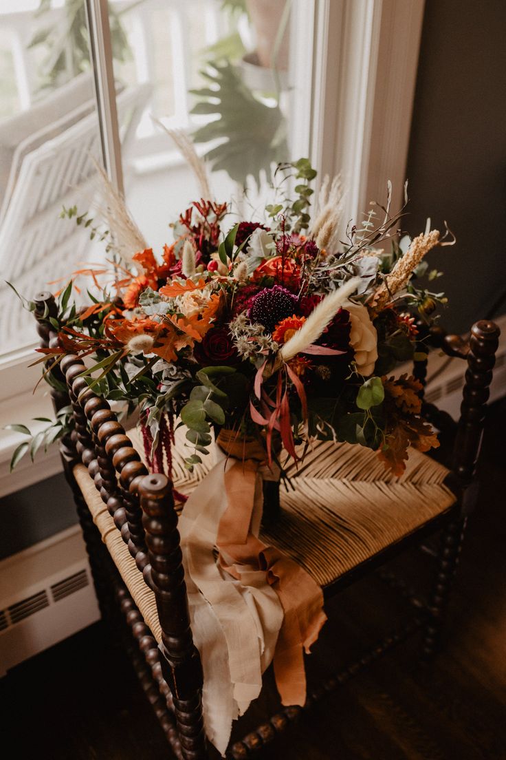 an arrangement of flowers is sitting on a chair