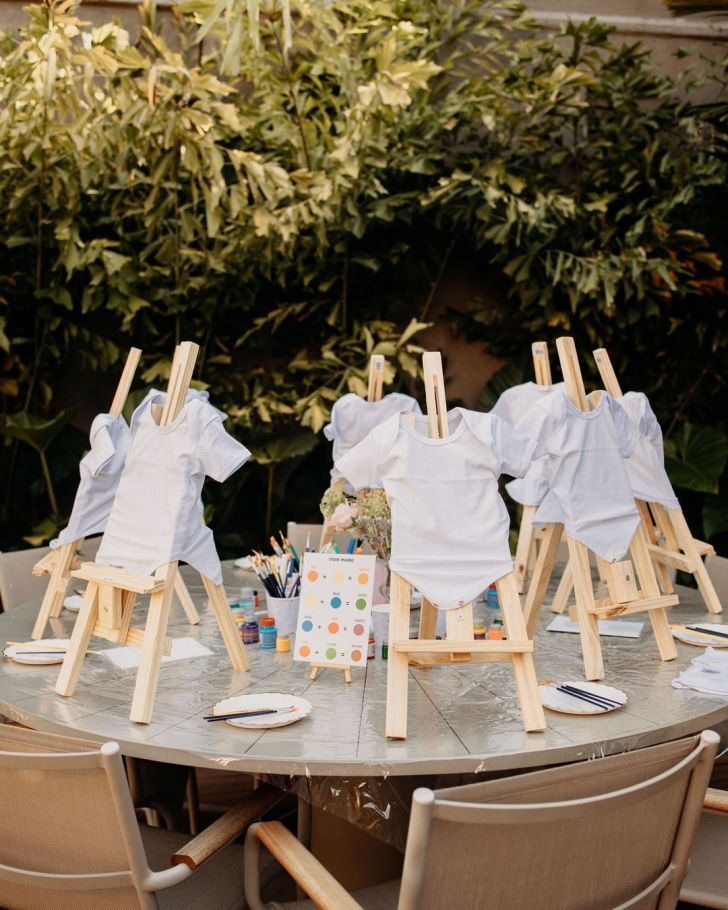 an outdoor table set up with clothes on easels