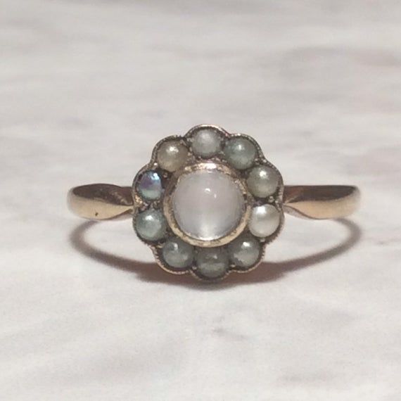 Stunning antique cabochon moonstone pearl  ring.A deeply lustrous Moonstone is set in a simple gold border, surrounded by a ring of antique pearls. The antique pearls are a dark creamy to silvery grey colour.The lustrous moonstone varies from a misty pale  silvery grey through to a dreamy dark misty grey, and set against the pearls, they make a lovely combination.The moonstone has natural inclusions, as is usual with a natural moonstone. The pearls are all original, except maybe the silvery grey Moonstone Antique Ring, Classic Moonstone Cabochon Ring For Anniversary, Vintage White Moonstone Ring, Vintage Moonstone Gemstone Ring For Anniversary, Moonstone Cabochon Ring For Anniversary, Anniversary Moonstone Cabochon Ring, Vintage Round Moonstone Ring, Vintage Cabochon Moonstone Ring For Anniversary, Vintage White Moonstone Ring For Anniversary