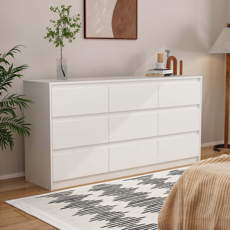 a bedroom scene with focus on the bed and dresser in the foreground, there is a rug on the floor