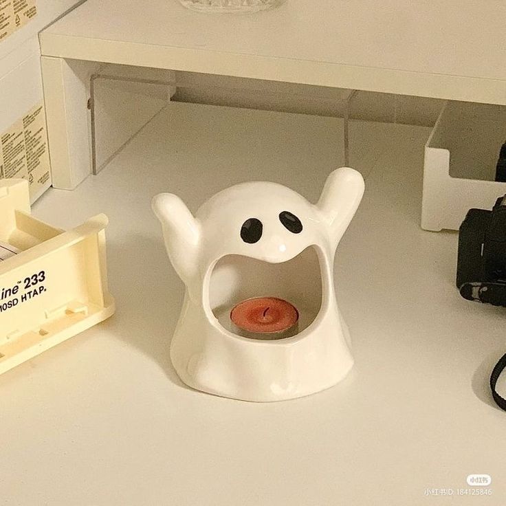 a white desk with a camera and some other items on top of it, including a toy ghost