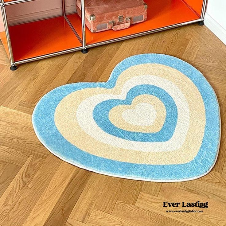 a heart shaped rug on the floor in front of an orange bookcase with suitcases