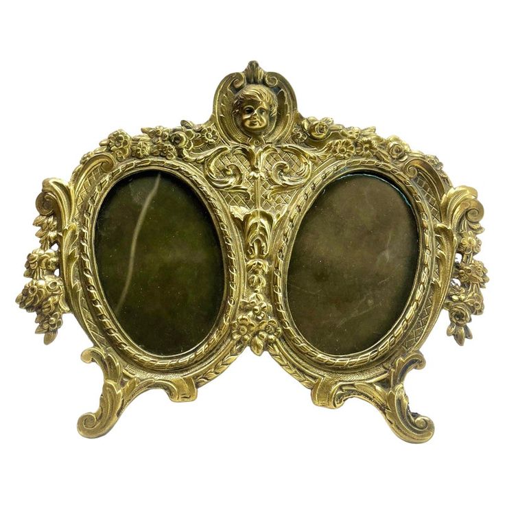 an ornate gold frame with two oval mirrors on it's sides, set against a white background