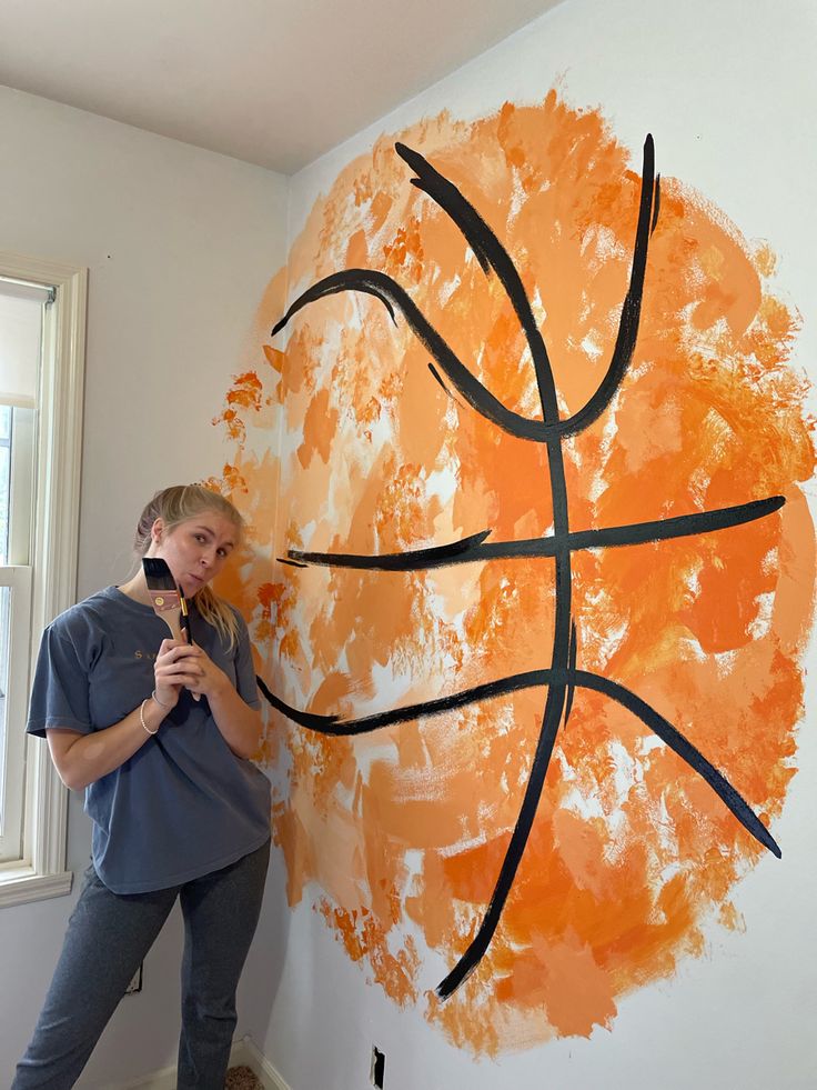 a woman standing next to a basketball painted on the wall