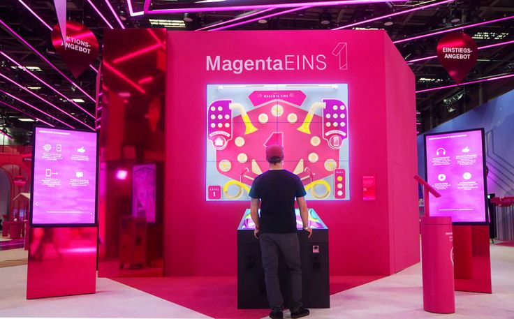 a man standing in front of a display with magenta ens on the screen