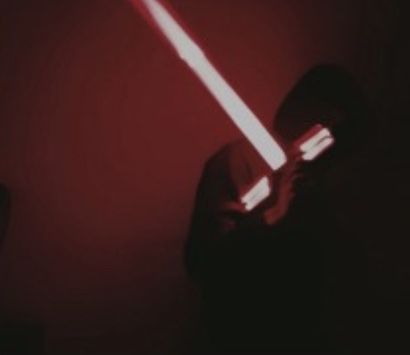 a person holding a light saber in their hand with the lights turned on and red background