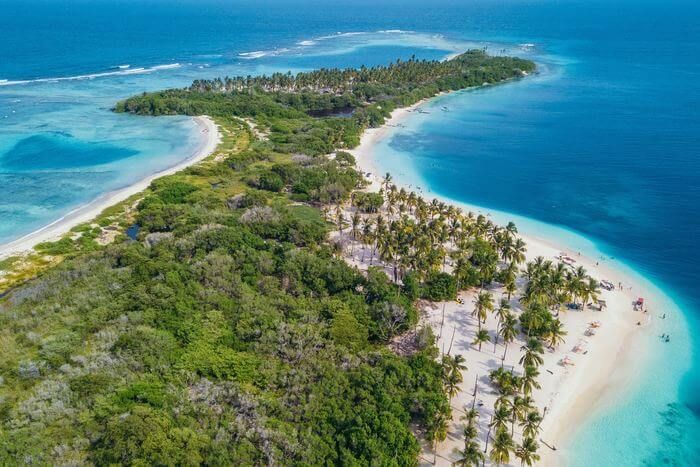 an island in the middle of the ocean with palm trees on it's sides