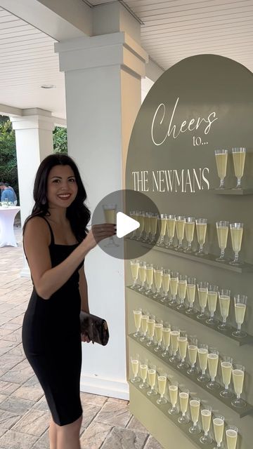 a woman standing in front of a sign with glasses on it and the words cheers to the newnans