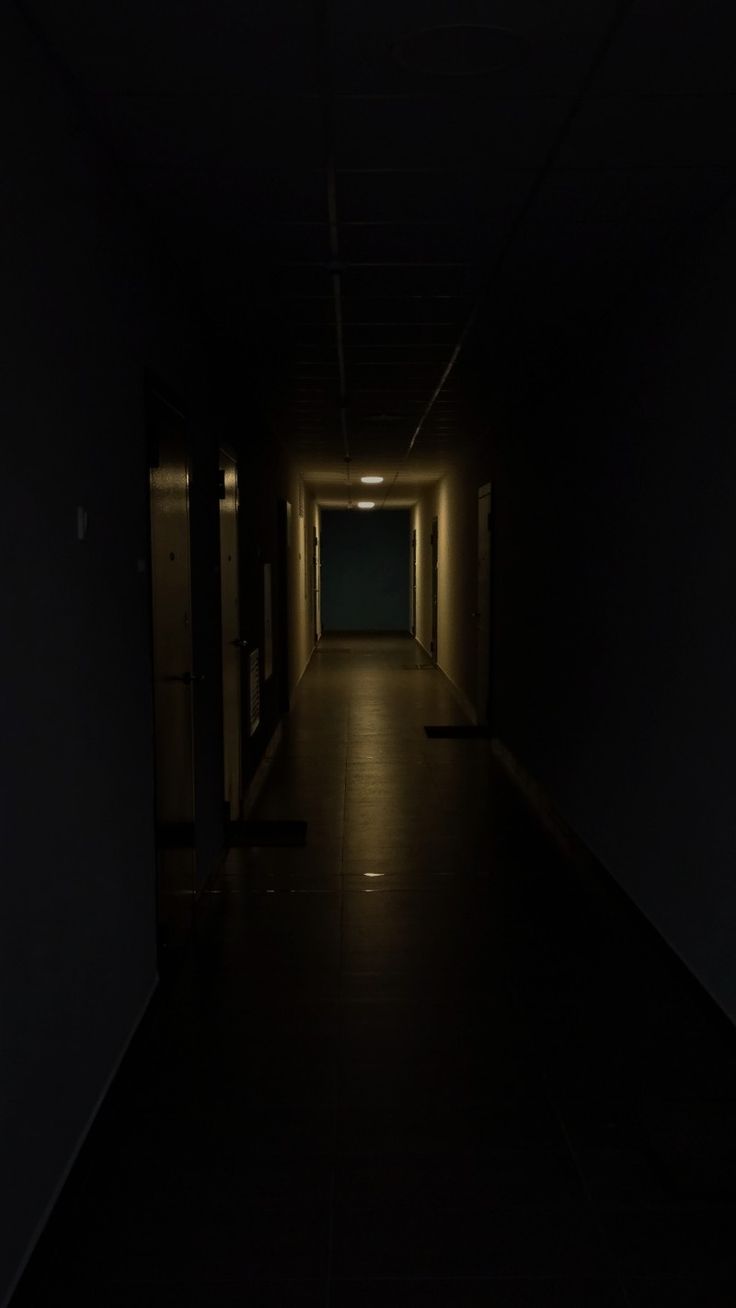 an empty dark hallway with light at the end