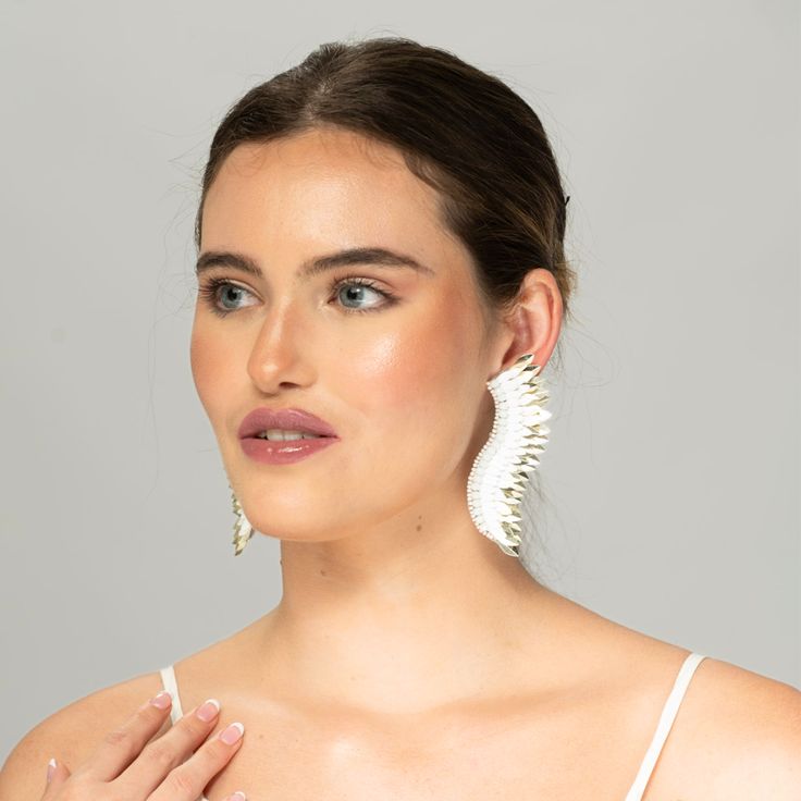 Bring the elegance of white gold into your ensembles in a fresh new way when you don the White Gold Small Wing Earrings at your next dinner party or wedding. Handmade with care, they are a statement piece that will match all your looks. The earrings boast layers of white and gold-toned beads arranged atop one another in a wing-like shape, creating the silhouette of these angel wing earrings. Size: Length: 3.5''/ Width: 1'' White Dangle Clip-on Earrings For Party, Modern White Single Pearl Earring, Wedding Dangle Plug Earrings, Chic White Gold Earrings For Evening, Elegant Silver Plug Earrings For Party, Modern White Pearl Earrings For Formal Occasions, Modern White Dangle Pearl Earrings, Modern White Earrings For Formal Occasions, White Modern Pierced Pearl Earrings