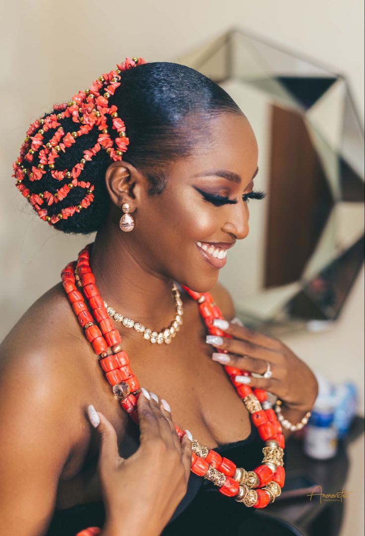 a woman in a black dress with red beads on her head and necklaces around her neck