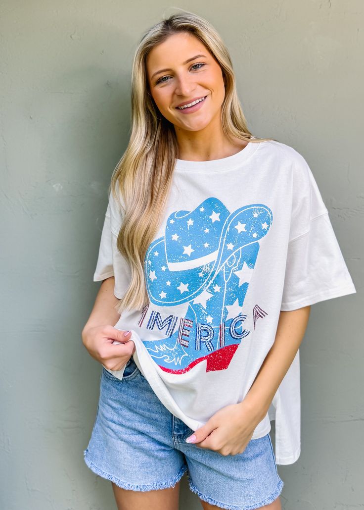 Step up your summer style in this playful Western boots graphic tee with 'America' sequin lettering embroidery. Perfect for Fourth of July festivities or just adding some fun and classic flair to your wardrobe. True to size Oversized fit intended Round neckline Pull on fit Sequin lettering embroidery Not lined 100% cotton Fabric has little stretch Casual Summer T-shirt With Embroidered Graphics, Summer Short Sleeve T-shirt With Embroidered Text, Trendy Pre-shrunk Tops For 4th Of July, Trendy Cotton Tops For 4th Of July, Trendy Graphic Print T-shirt For 4th Of July, Casual 4th Of July Top With Text Print, Trendy T-shirt With Embroidered Text For Summer, Trendy Summer T-shirt With Embroidered Text, Trendy Tops For 4th Of July With Relaxed Fit