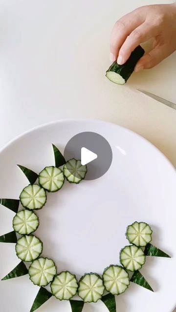 someone is cutting up some food on a white plate with green leaves in the shape of a wreath