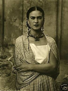 an old black and white photo of a woman with her arms crossed, wearing earrings