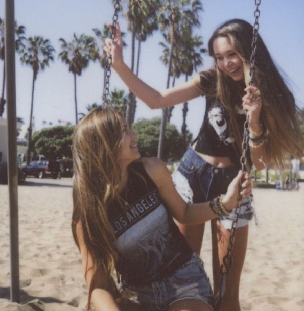 two girls on the beach with palm trees in the background