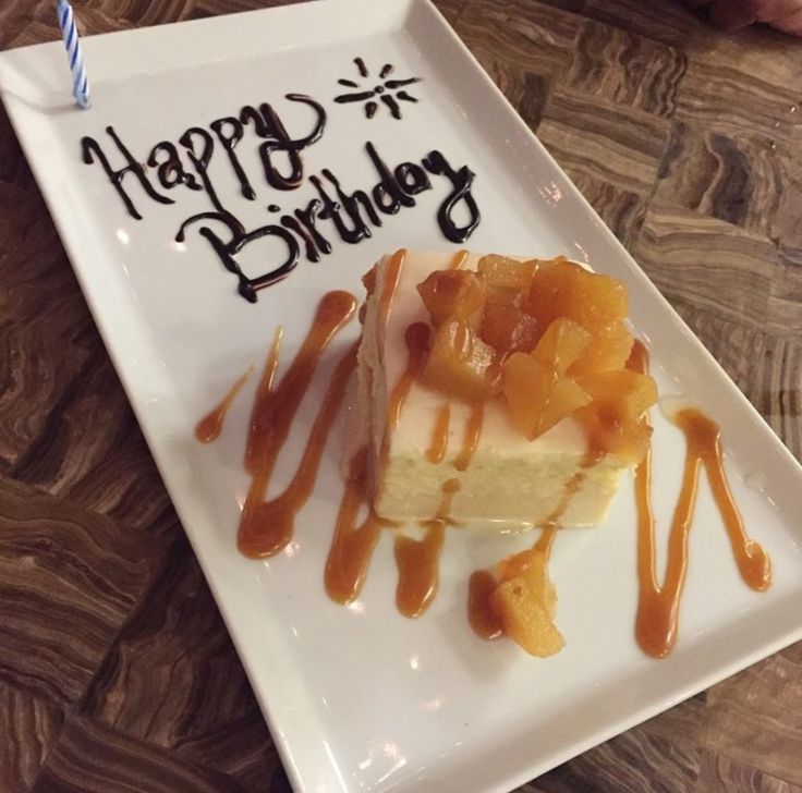 a piece of cake on a white plate with caramel drizzle and happy birthday written on it