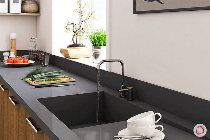 a kitchen with black counter tops and white dishes on the sink, along with an open window