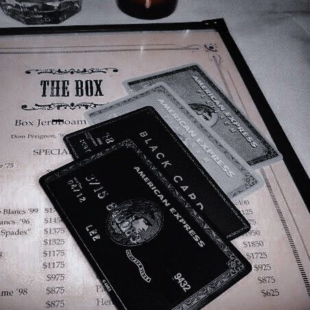 two black cards sitting on top of a table next to a candle and some glasses