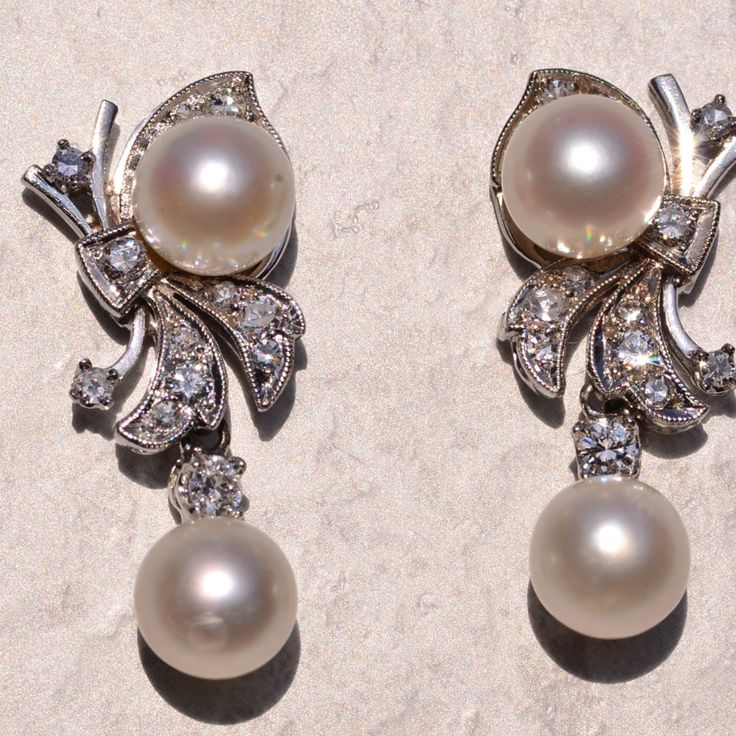 The 182nd Street: Hollywood Glam Era Pearl And Diamond Dangler Earrings. The Earrings Each Feature An Akoya Cultured Pearl Dangling With A Round Brilliant Cut Natural Diamond At The Bottom. Above Is A Bow Motif Set With Transitional Round Brilliant Cut Natural Diamonds With An Additional Akoya Pearl. The Diamonds Have An Approximate Total Weight By Measurement Of 0.52 Carats. The Pearls Have A Measurement Of 7.5 Millimeters. The Earrings Are Finished With Posts And Push Style Backs And Are Crafted In 14 Karat White Gold, Measuring Just Under 1.25 Inches In Total Length. White Clip-on Pearl Earrings For Evening, Elegant Diamond White Clip-on Jewelry, Exquisite White Diamond Earrings For Evening, Elegant Platinum Diamond Earrings For Anniversary, Luxury Platinum Pearl Earrings For Formal Occasions, Luxury White Clip-on Diamond Earrings, Elegant Platinum Diamond Earrings For Formal Occasions, Elegant Formal Clip-on Diamond Earrings, Formal Bridal Diamond Clip-on Earrings