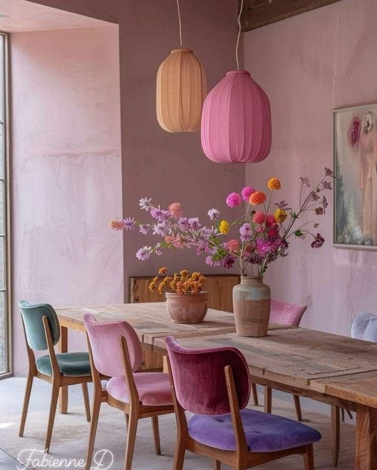 a wooden table topped with purple chairs next to a vase filled with flowers