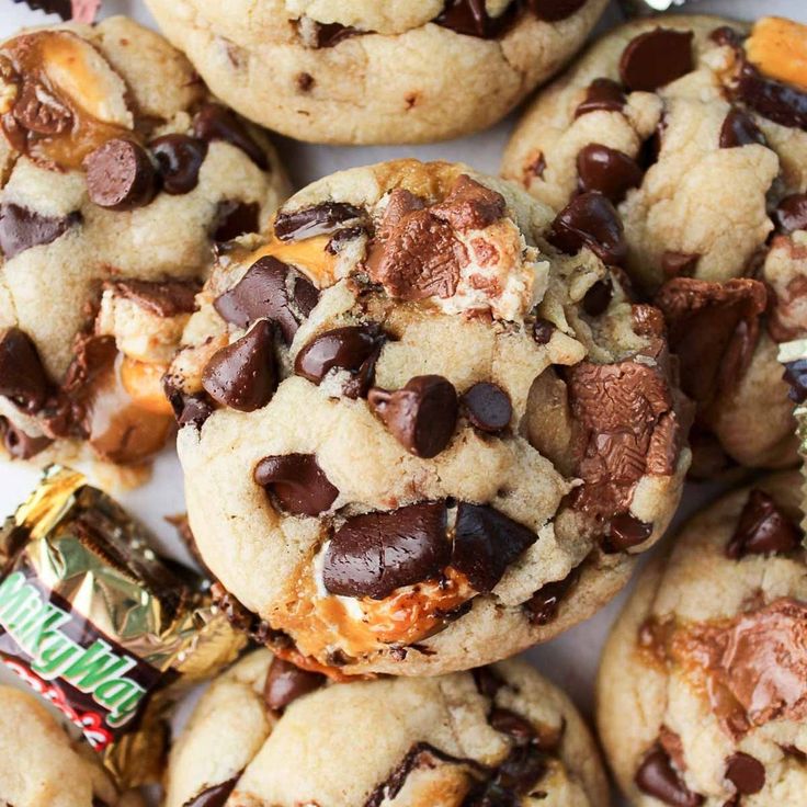 chocolate chip cookies are piled on top of each other with candy bar in the middle