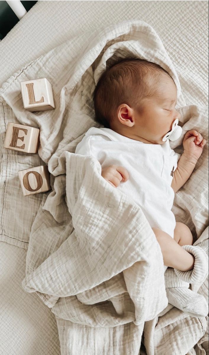 a baby laying on top of a bed next to blocks