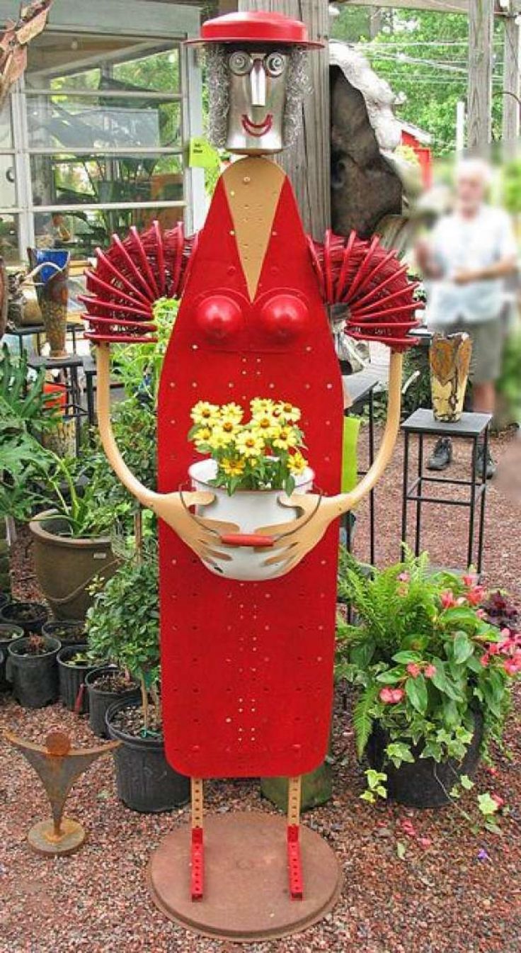 a large red statue holding a potted plant in it's hands