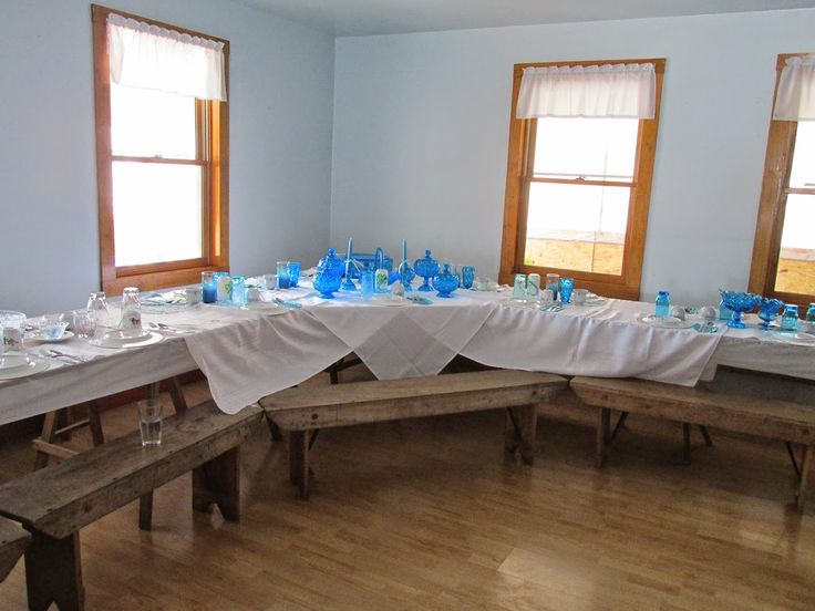 a long table is set up with blue glassware and place settings for the guests