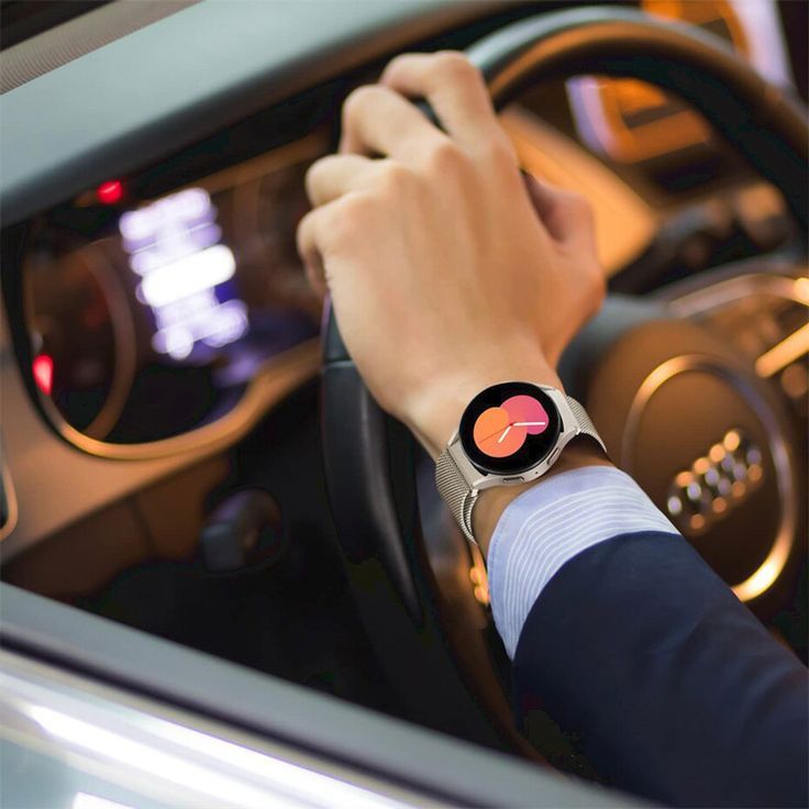 a man driving a car with his hand on the steering wheel while wearing a smart watch