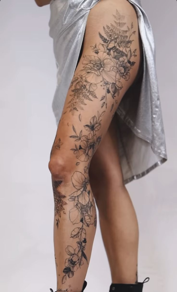 a woman's legs with tattoos and flowers on them