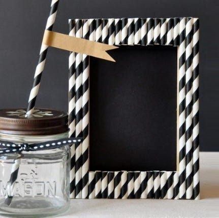 a mason jar with a black and white striped straw in it next to a chalkboard