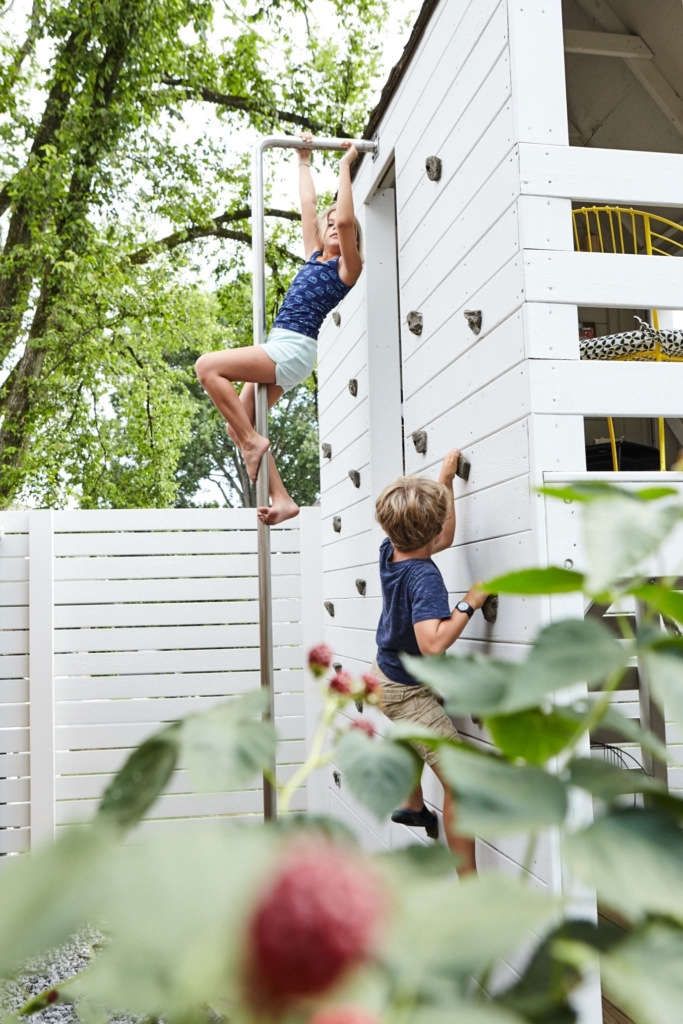 two children climbing up the side of a house