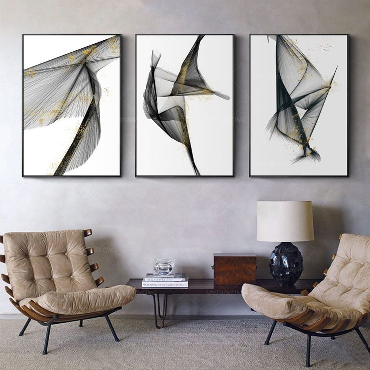 three abstract paintings hang on the wall above two chairs and a table in a living room