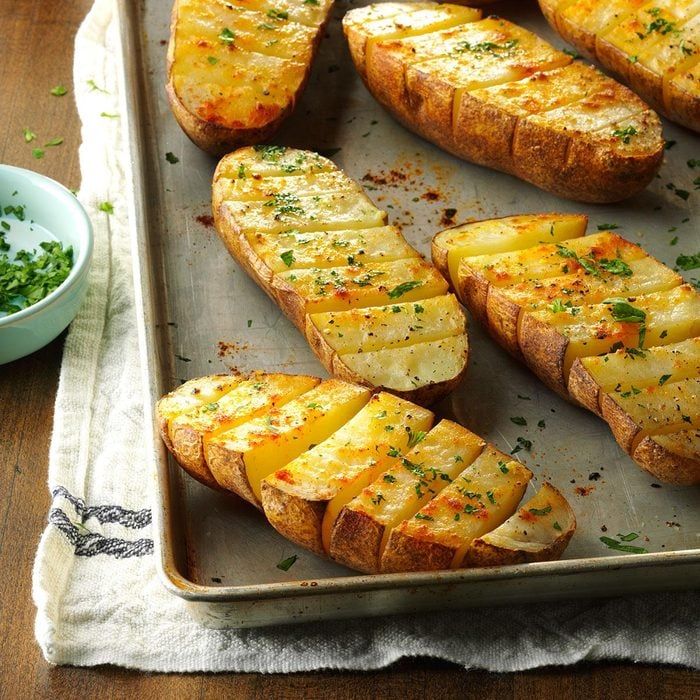 baked potatoes with cheese and herbs on a baking sheet