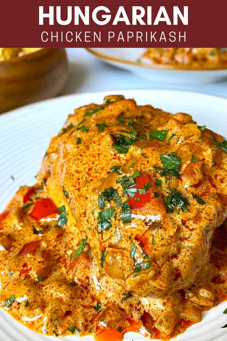 a white plate topped with meat covered in sauce and garnished with green leaves