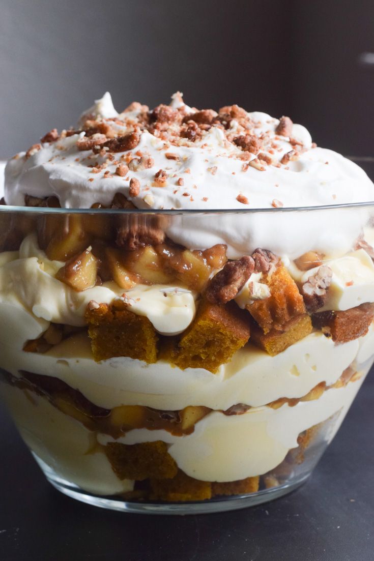 there is a dessert in the glass bowl on the table with whipped cream and walnuts