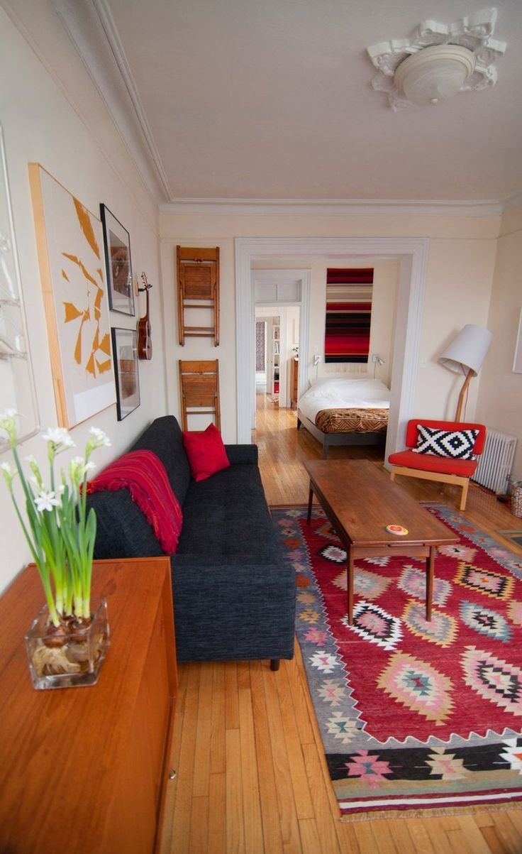 a living room filled with furniture next to a wooden table and white flowers on top of a rug