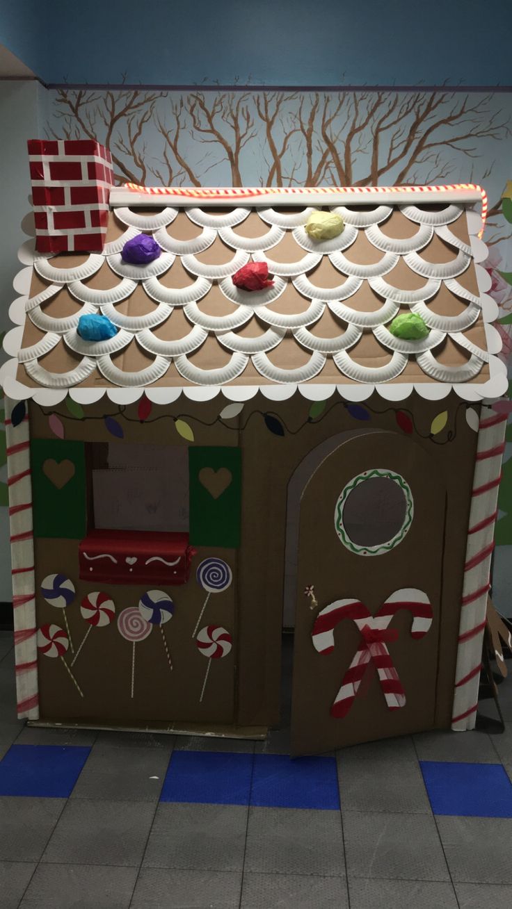 a cardboard gingerbread house with candy canes on the roof