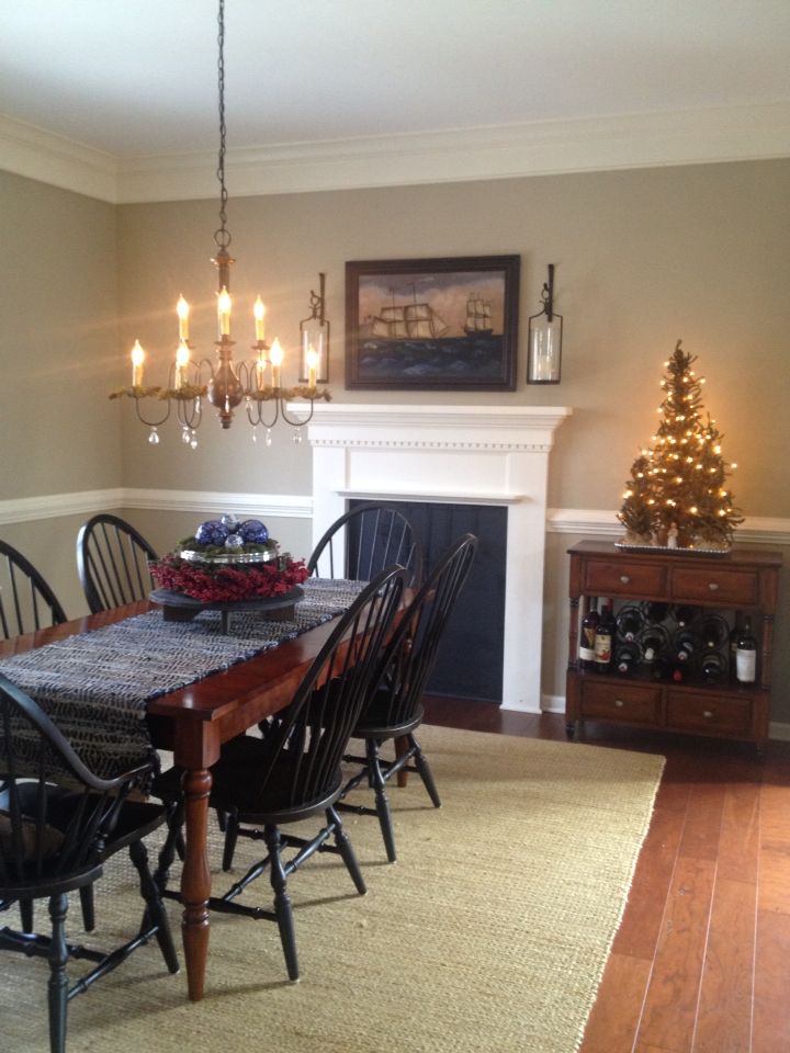 a dining room table with black chairs and a christmas tree in the corner behind it