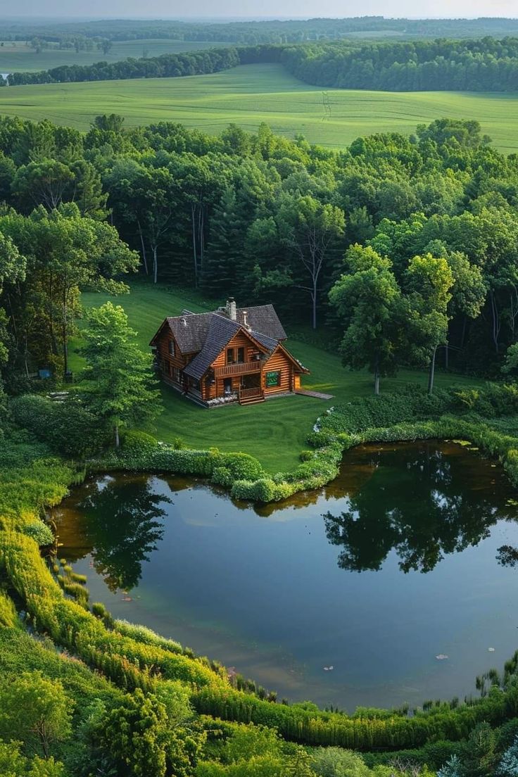 an aerial view of a house in the middle of a green field with trees around it