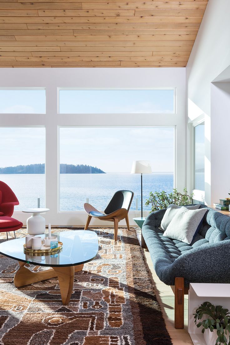 a living room filled with furniture next to a large window overlooking the water and mountains