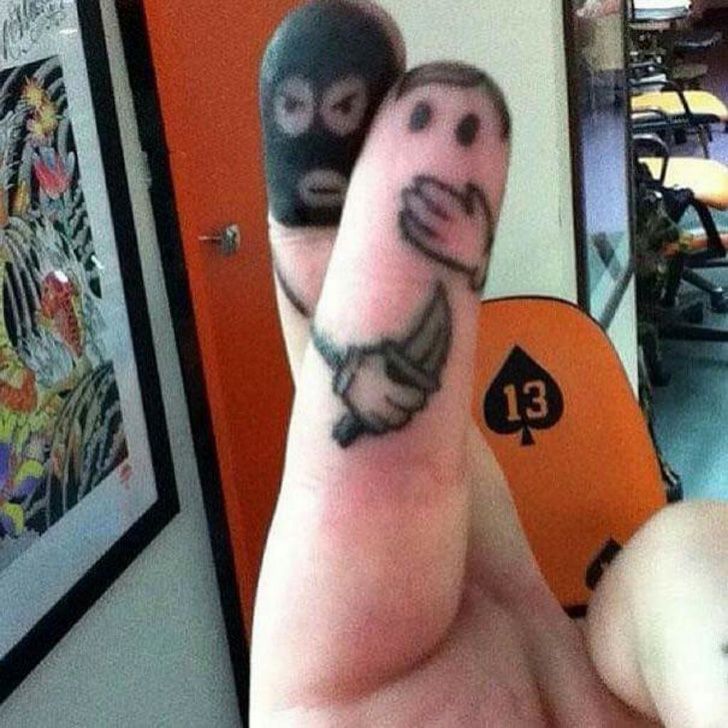 a person with two faces drawn on their fingers and one has a smiley face tattooed on his thumb