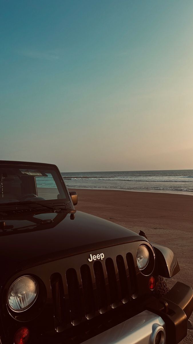 the jeep is parked on the beach near the water