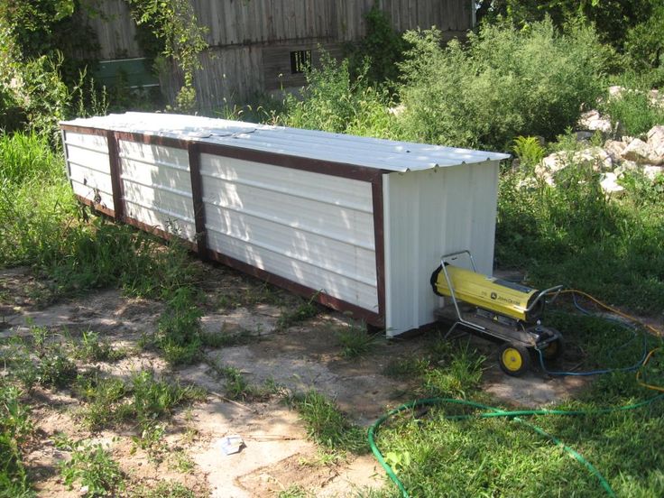 an outhouse in the middle of a field with a hose hooked up to it