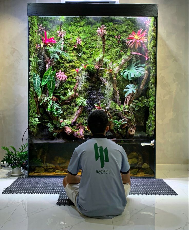 a man sitting in front of a large aquarium