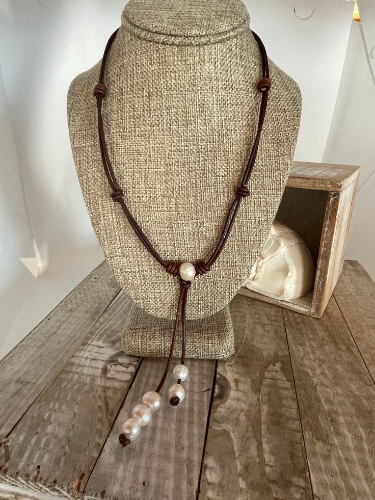 Wear this boutique style necklace every day since it will go with so many styles and colors. See pictures for the up close and personal to see the beauty of this dark cherry brown leather. What I love about this color is the leather has variations in the intensity of the staining throughout the necklace. It is a 2mm round leather that has has been doubled and barrel knotted in strategic places. The leather is supple and soft and it should continue to distress as it is worn.  There is a creamy white freshwater pearl in the center of the necklace. This pearl has been barrel knotted to secure it. Below the center bead you will find a tassel of two strands of leather with creamy freshwater pearls intended to dangle. The pearls are all cultured and there are no two alike. These pearls vary in s Cherry Brown, Up Close And Personal, Pearls Necklace, Round Leather, Boutique Style, White Freshwater Pearl, Style Necklace, Creamy White, Magnetic Closure