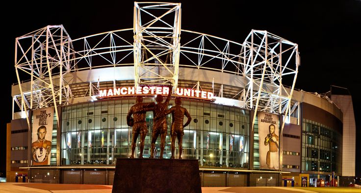 the manchester united stadium is lit up at night